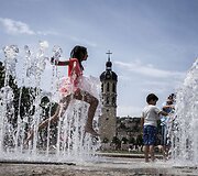 Vaikai kar&scaron;tą vasaros dieną vėsinasi fontane