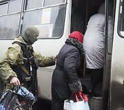 Ukrainos karys padeda moterims lipti į autobusą, kuriuo evakuojami žmonės i&scaron; Debalcevės miesto