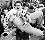 Futbolo sirgalius ne&scaron;a draugą, kuris buvo sužeistas stadione sugriuvus sienai per &bdquo;Juventus&ldquo; ir &bdquo;Liverpool&ldquo; komandų susitikimą Europos taurės finale, Briuselyje. (1985 m. gegužės 29 d.)