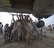 Pakistane potvynio nuvarginti žmonės kabinasi už karinio sraigtasparnio, atgabenuosio maisto (2010 m. rugpjūčio 7 d.)