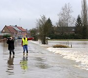 Žurnalistai stovi ant apsemto kelio