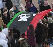 Protestuotojos laiko Libijos vėliavą.