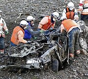 Gelbėtojai prie sulamdyto automobilio.