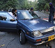 Studentai automobiliu užstato kelią vedantį į universitetą. 