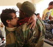 Libijos sukilėlis ne&scaron;a sužeistą kolegą.