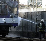 Gaisrininkai gesina padegtą keleivinį traukinį.