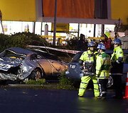Gelbėtojai stovi netoli suniokoto automobilio
