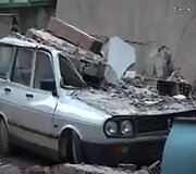 Krentančių nuolaužų apgadintas &scaron;alia pastato stovėjęs automobilis