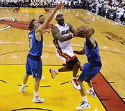 LeBronas Jamesas veržiasi pro Dirką Nowitzkį (kairėje) ir Tysoną Chandlerį