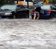 Vyras stumia autombolį, kuris jam užgeso apsemtoje Vuhano miesto gatvėje.