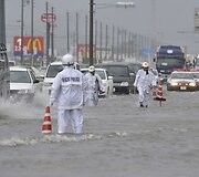 Tojokavoje automobiliai važiuoja apsemtu keliu.