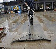 Vyras valo potvynio sune&scaron;tą purvą.