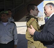 Izraelio ministras pirmininkas Benjaminas Netanyahu (de&scaron;inėje) sveikina į &scaron;alį sugrįžusį Giladą Shalitą
