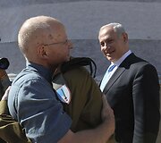 Izraelio ministras pirmininkas Benjaminas Netanyahu (de&scaron;inėje) žiūri į apsikabinusius Giladą Shalitą ir jo tėvą.