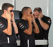 Lewis Hamiltonas (centre) užsikime&scaron;ęs ausis kol bandomas &bdquo;Formulės-1&ldquo; variklis