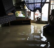 Moteris apsemtame kambaryje žiūri televizorių.