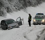 Policininkas stovi &scaron;alia nuo kelio nuslydusio automobilio