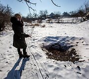 Marjinkos gyventoja Oksana rodo &scaron;alia tako sprogusio artilerijos sviedinio duobę