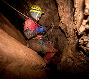 Speleologė specialios įrangos pagalba leidžiasi į urvo gilumą