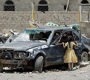 Moteris Jemeno sostinėje prie apgadinto automobilio po Saudo Arabijos oro atakų