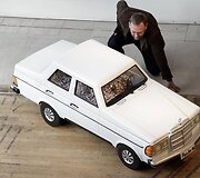 Darbuotojas pozuoja prie &bdquo;Mercedes-Benz&ldquo; automobilio formos karsto