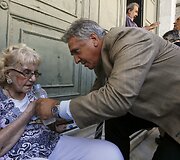 Banko tarnautojas padeda nualpusiai moteriai laukusiai eilėje prie banko
