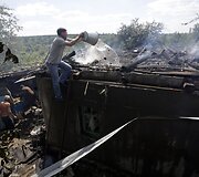 Ukrainos kaimo gyventojai gesina degantį savo namą po separatistų ap&scaron;audymo