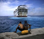 Pora migrantų stebi i&scaron;plaukiantį laivą Graikijos saloje