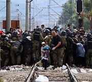 AP_Makedonijos policininkai bando užblokuoti kelią besiveržiantiems migrantams