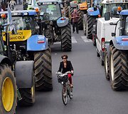 Paryžietė važiuoja dviračiu tarp protestuojančių ūkininkų technikos