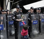 Migrantų vaikas įteikia gėlę Turkijos pareigūnams
