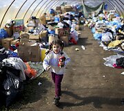 Migrantų mergaitė i&scaron;eina su žaislu i&scaron; Vengrijoje įrengto labdaros punkto