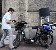 Yue Banghai ant elektrinio dviračio pritvirtino monitorių akcijų biržoms stebėti