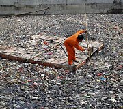 Darbininkas valo &scaron;iuk&scaron;les i&scaron; upės Indonezijoje