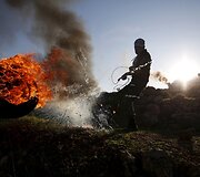 Protestuojantis palestinietis paspiria degančią padangą