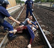 Vengrų policininkai bando sulaikyti vyrą, pargriovusį savo žmoną su kūdikiu