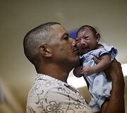 Tėtis laiko mikrocefalija sergantį savo vaiką Brazilijoje