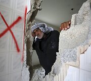 Palestinietis prie savo sugriautų namų