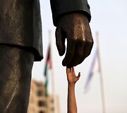 Vyras liečia Nelsono Mandelos skulptūros ranką Pietų Afrikos Respublikoje