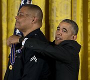 Prezidentas Barackas Obama bando užsegti medalį Los Andželo policininkui