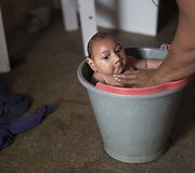 Brazilė prausia savo vaiką gimusį su mikrocefalija