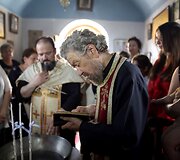 Stačiatikių kunigas skaito pamokslą prie&scaron; krik&scaron;to apeigas Graikijoje