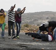 Užsimaskavę Izraelio kariai tarp protestuojančių palestiniečių