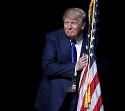 Kandidatas į JAV prezidentus Donaldas Trumpas apkabina vėliavą
