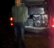 Kontrabandines cigaretes vežęs vyras prie automobilio