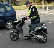 Policininkas apžiūri sudaužytą mopedą