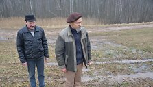 Algirdas Milukas (kairėje) ir jo kamynas Juozas Volungevičius stebi, kaip upelis, susidarantis keletą mėnesių per metus, per kelią teka i&scaron; Bak&scaron;ių ežero į Teizų.