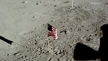 Nuotrauka padaryta po astronautų pasivaik&scaron;čiojimo, jiems sugrįžus į &bdquo;Erelį&ldquo;. Pro iliuminatorių matyti tebestovinti JAV vėliava, ant &scaron;tatyvo palikta vaizdo kamera ir daugybė pėdsakų. 1969 m. liepos 20 d.