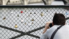 Turistas fotografuoja spynas ant Pont des Arts tilto turėklų.