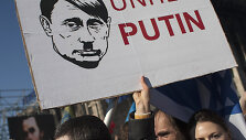 A woman holds a sign depicting Russian President Vladimir Putin as Adolf Hitler as she attends a rally at Independence Square in Kiev March 9, 2014. Russian forces tightened their grip on Crimea on Sunday despite a U.S. warning to Moscow that annexing the southern Ukrainian region would close the do